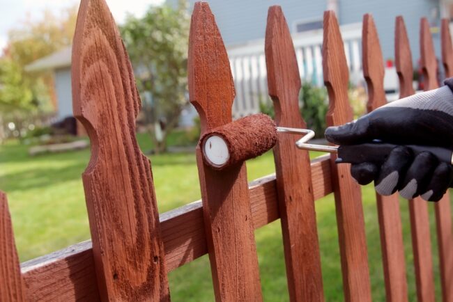 Painting a fence brown.